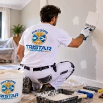 Pintor de Tristar Company aplicando masilla en una pared para reparar y alisar la superficie antes de pintar