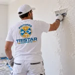Pintor profesional de Tristar Company eliminando gotelé y alisando una pared interior