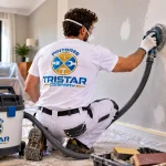 Pintor de Tristar Company lijando una pared con aspiración antes de aplicar pintura