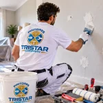 Pintor de Tristar Company reparando agujeros y grietas en una pared antes de pintar